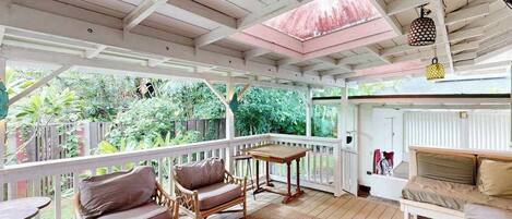 A covered outdoor area with wooden furniture, a table, and a sofa.