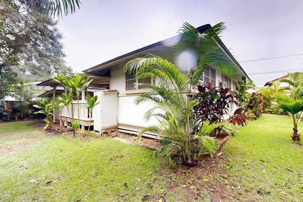A house with a covered porch, surrounded by lush greenery and a well-maintained lawn.