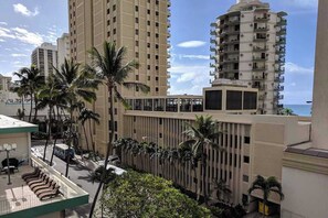 Un hotel moderno de gran altura, con varias plantas, palmeras y vistas al océano.