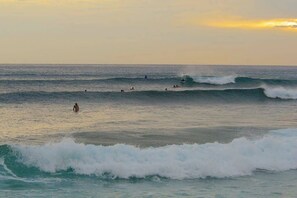 Una playa con olas y gente en el agua.