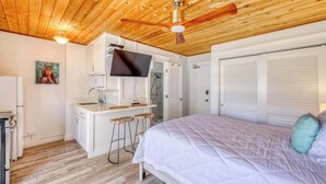 Ein Zimmer mit Bett, Küchenzeile, Deckenventilator und Fernseher.