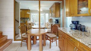 Una cocina con armarios de madera, encimera de granito y un comedor con mesa y sillas redondas.