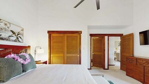 Una habitación de hotel con cama, armario de madera y un cuadro en la pared.