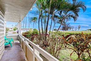 A covered outdoor area with a view of a grassy field and palm trees. - NEW Fall $pecial Kapaa 1BR End Unit with 3 Pools and Beach Path (Kapaa)