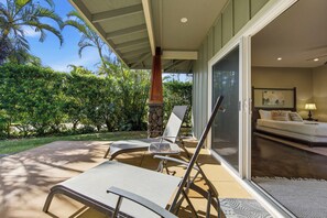 Eine Terrasse mit zwei Lounge-Stühlen, einer Steinpfeiler und Blick ins Innere durch eine Glastür.