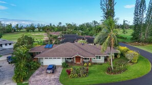 A residential property with a two-story house, solar panels, a driveway, and a well-maintained lawn. - The Palm House Family Retreat at Princeville - Mins to Beach, Shops, Dining (Princeville)