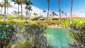Una località turistica tropicale con palme, una piscina e capanne con tetti di paglia.