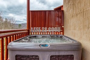 A hot tub on a balcony with a wooden railing and a sign that reads 'LIFE IS GOOD.' - Eat, Drink and Be Beary (Sevierville)