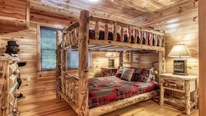 Interior de una cabaña de madera con una litera, una mesita de noche y una lámpara.