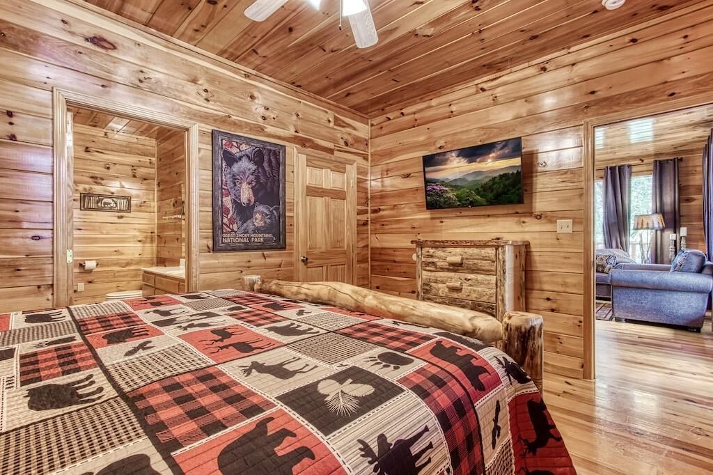 A log cabin room with a bed, a poster, a painting, and a blue sofa.
