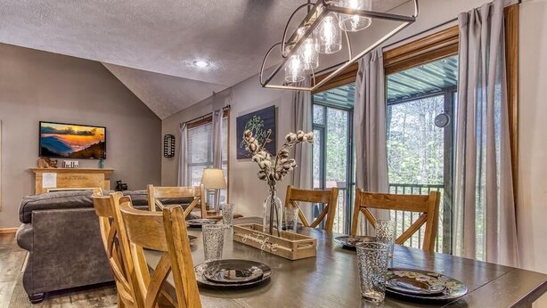 A dining area with a wooden table set for four, surrounded by wooden chairs. - Foxes Den (Pigeon Forge)
