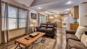 A spacious living room with a sofa, coffee table, and a kitchen in the background. - Foxes Den (Pigeon Forge)