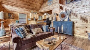 A wooden interior with a brown leather sofa, a wooden dining table, and a staircase. - Goldilock's Cottage (Sevierville)
