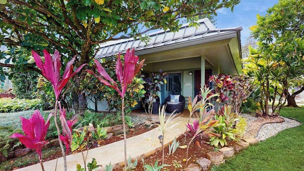 Una casa con jardín, un sendero y un porche.