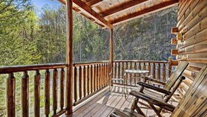 Um deck de madeira com guarda-corpo, uma mesa e duas cadeiras.