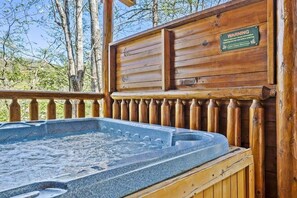 Ein Whirlpool in einer Holzhütte mit einem Warnschild und Blick auf Bäume.