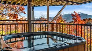 Ein Whirlpool auf einem Balkon mit Blick auf Herbstbäume und Berge.