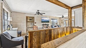 A rustic interior with a wooden bar, seating, ceiling fans, and a mountain view. - Grassy Paradise (Gatlinburg)