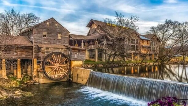 Eine historische Wassermühle mit Holzbauten und einem großen Wasserrad.