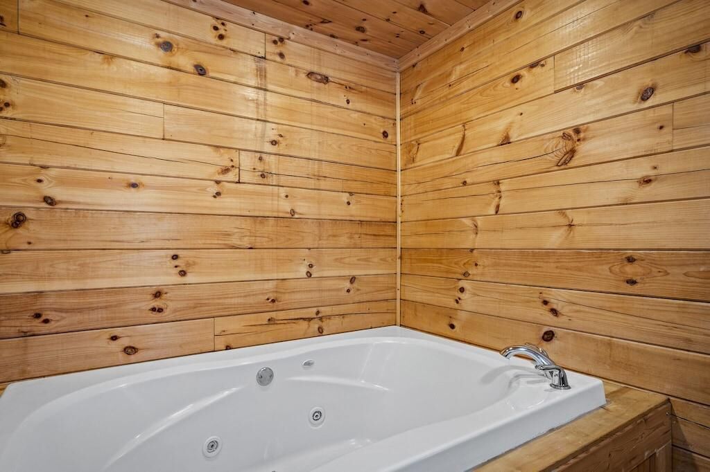 Una habitación con paneles de madera, una bañera blanca y un solo grifo.