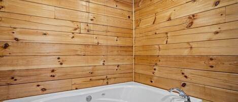 Una habitación con paneles de madera, una bañera blanca y un solo grifo.