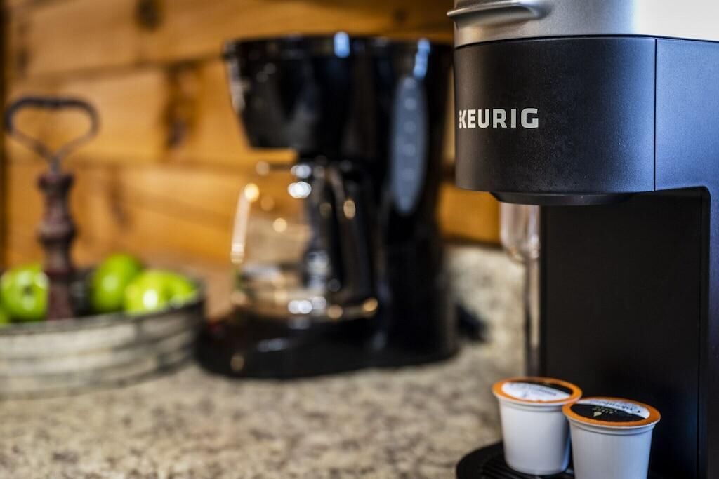 En Keurig kaffemaskine med to kaffekapsler på en bordplade.