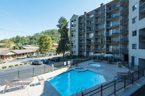 Ein mehrstöckiges Gebäude mit Swimmingpool, Außenbereich und Parkplatz.