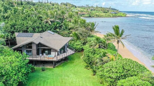 A modern house with a deck overlooking a beach and ocean. - NEW Anahola 3BR Beachfront Estate with Private Hot Tub TVNCU#1305 (Anahola)