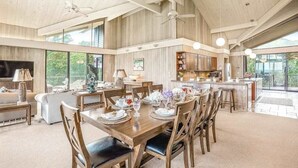 A spacious dining area with a high ceiling, wooden beams, and large windows offering views of the outdoors. - NEW Anahola 3BR Beachfront Estate with Private Hot Tub TVNCU#1305 (Anahola)
