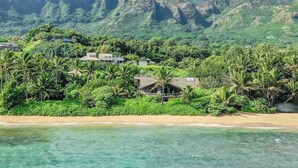 A coastal resort with beachfront villas, lush greenery, and mountains in the background. - NEW Anahola 3BR Beachfront Estate with Private Hot Tub TVNCU#1305 (Anahola)