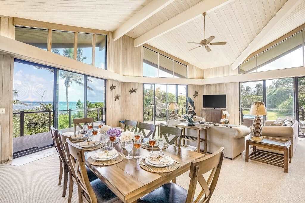 A spacious living area with a dining table set, a sofa, and a television.
