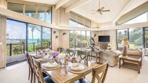 A spacious living area with a dining table set, a sofa, and a television. - NEW Anahola 3BR Beachfront Estate with Private Hot Tub TVNCU#1305 (Anahola)