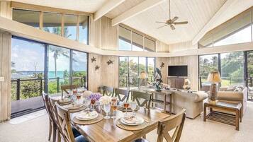 A spacious living area with a dining table set, a sofa, and a television.