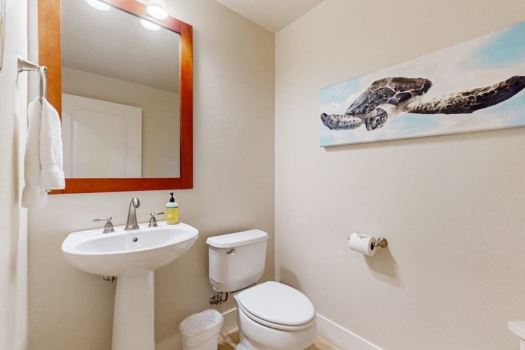 Een badkamer met een wastafel, toilet en een schilderij van een zeeschildpad aan de muur.
