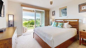 Un dormitorio con cama, ventilador de techo, escritorio, silla y vistas al exterior.