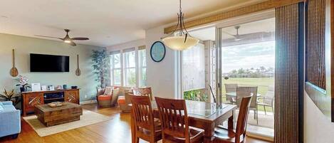 Amplia sala de estar con mesa de comedor, sillas, televisor y un gran ventanal con vistas al exterior.