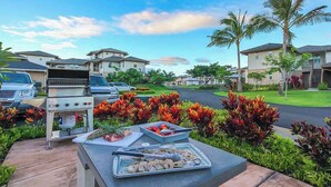 Zona residencial con casas, una parrilla y una mesa con comida.