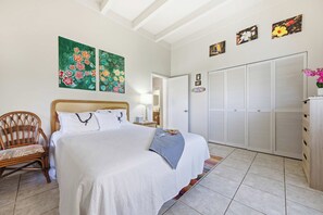 Une chambre à coucher avec un lit, une chaise, une armoire et deux tableaux accrochés au mur.