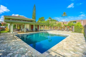 A swimming pool with a stone deck, a covered seating area, and a building with a tiled roof. - *New* Step-Free Princeville Stay with Two Lanais and Pool (Princeville)
