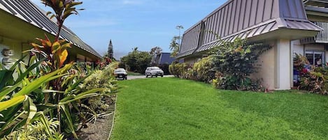 A residential area with a well-maintained lawn, parked cars, and houses with sloped roofs.