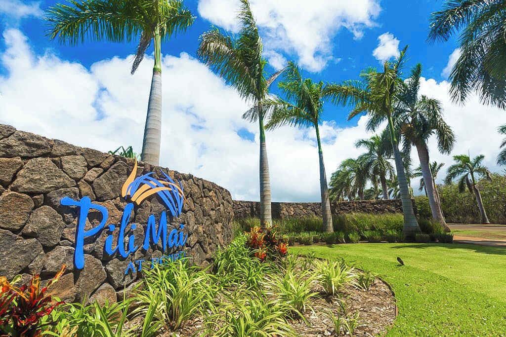 A stone wall with a sign that reads 'Pili Mai At The Resort.'
