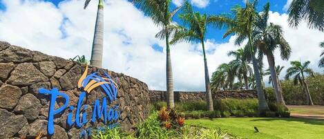A stone wall with a sign that reads 'Pili Mai At The Resort.'