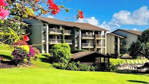 Un hôtel à plusieurs étages doté de balcons, d’une pelouse bien entretenue et d’un espace extérieur aménagé pour s’asseoir.