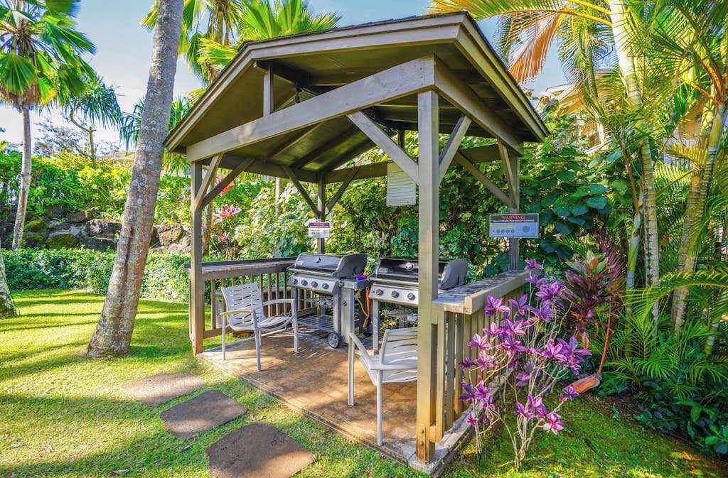 A covered outdoor grill area with seating and a sign.
