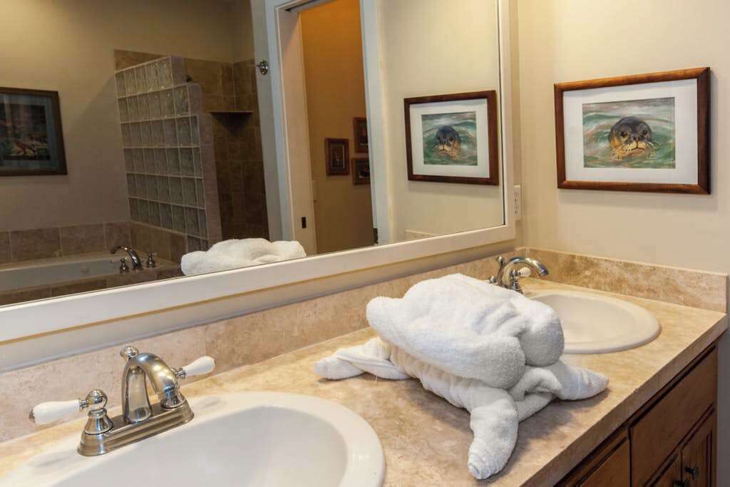 A bathroom with two sinks, a large mirror, and framed artwork on the wall.