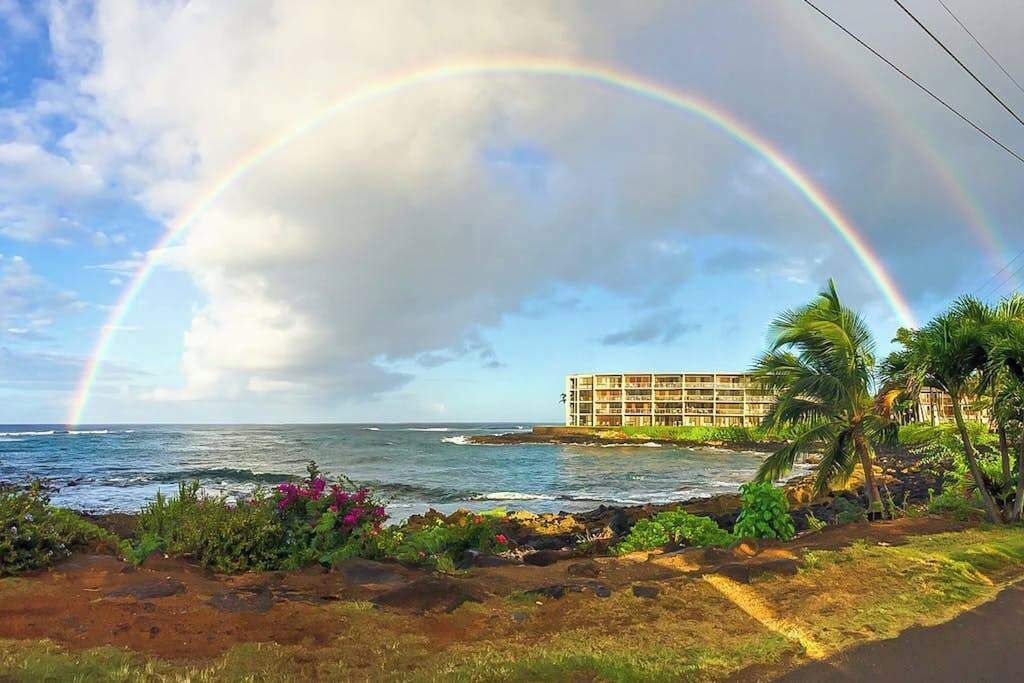 Een hotel aan de kust met uitzicht op de oceaan en een regenboog.