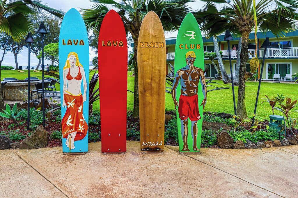 Vier surfboards met de aanduidingen 'Lava', 'Lava', 'Beach' en 'Club' in een resort omgeving.
