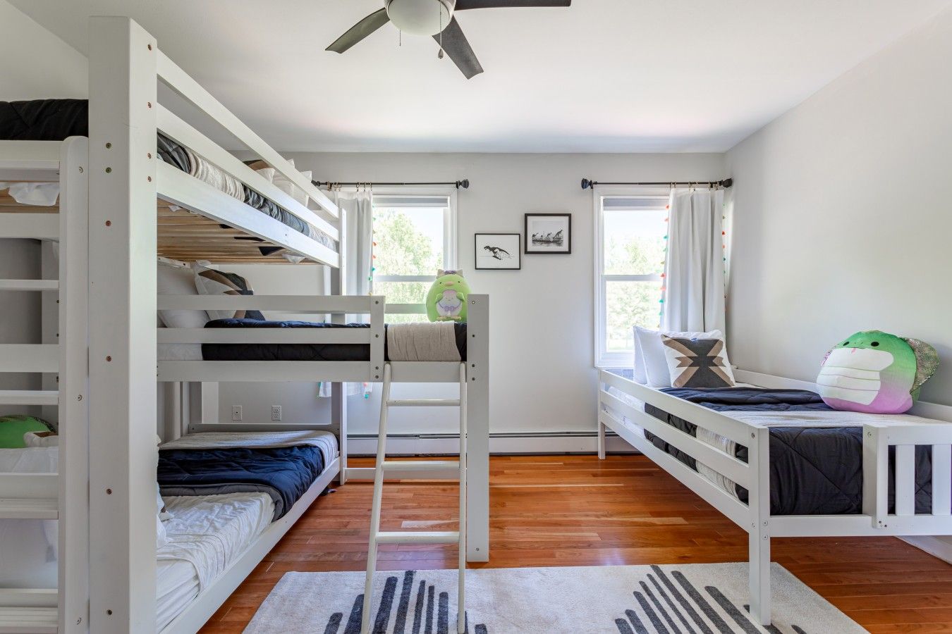 Une chambre avec des lits superposés, un ventilateur de plafond et une fenêtre avec des rideaux.
