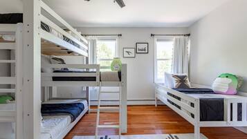 Une chambre avec des lits superposés, un ventilateur de plafond et une fenêtre avec des rideaux.