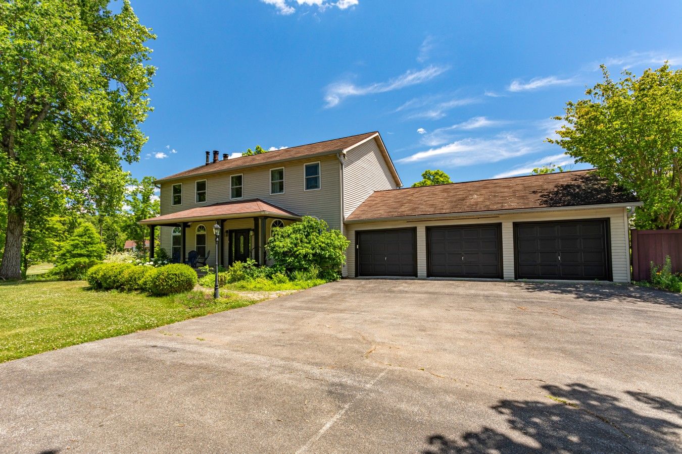A two-story house with a garage, a covered porch, and a well-maintained lawn.